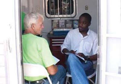 A patient talks with ENT resident Dr. Ajani Nugent in a mobile unit at a community head and neck cancer-screening event.