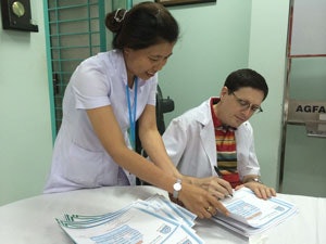 Dr. Brent Senior signs a large stack of paperwork for one of the nurses