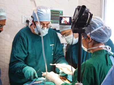 Surgical video conferencing. Dr. Paul Konowitz, assisted by Drs. Harsh Gupta and Neeti Kapre, leads the surgical workshop though his dissection which is being live streamed to the adjacent delegate room for discussion.