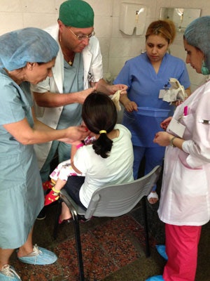 Salpy Akaragian, RN, (far left) with Artur Shukuryan, MD, (second from left) changing a mastoid dressing on a cochlear implant recipient.