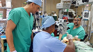 John Sinacori, MD, observes as Mauricio Loredo, MD, performs ear surgery. At right is anesthesiologist Matt Cecchini, MD.