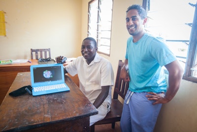 Figure 3. Moses Gona (left) and Asitha Jayawardena, MD, MPH (right) demonstrating the Firefly otoscope and a tympanic membrane they photographed during their screening.