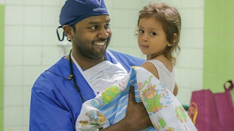 Dr. Sivam carries a returning patient to the operating room.