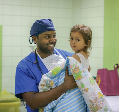 Dr. Sivam carries a returning patient to the operating room.