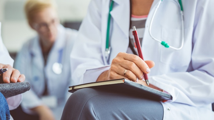 Lower body shot of a medical professional sitting in a classroom setting