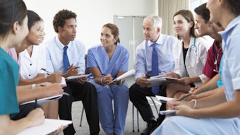 Group of medical professionals seated in a semi-circle taking notes