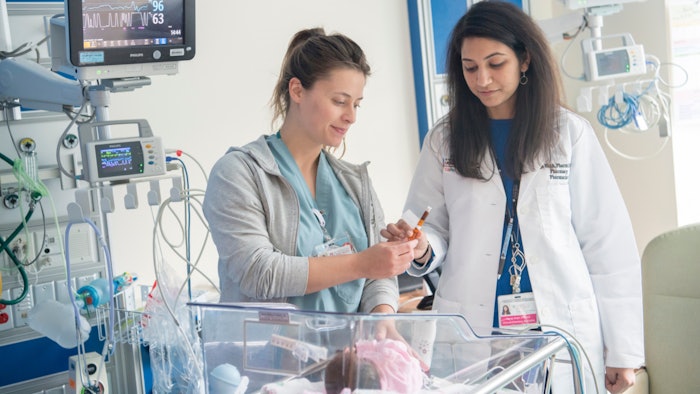 Female medical professionals examining a sample from a baby in a hospital