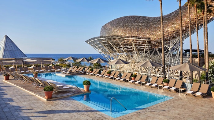 Amidst the green of the vegetation and the blue of the Mediterranean, guests can enjoy the pool at the Hotel Arts Barcelona.
