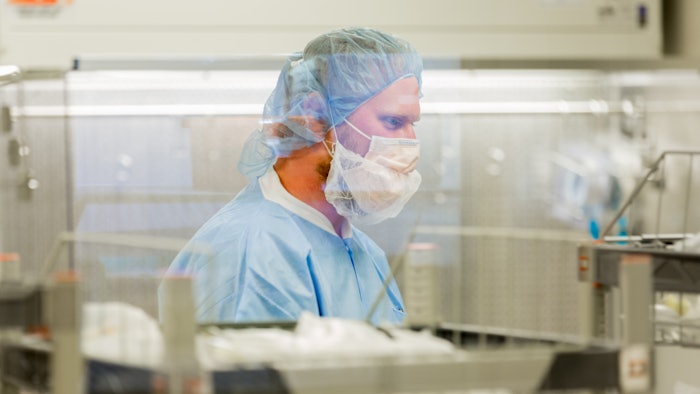 Picture of a pharmacist in a lab wearing protective gear.