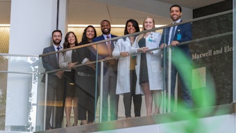 Photo of seven medical professionals standing behind a railing.