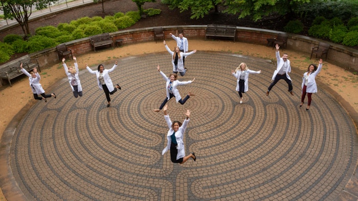 Photo of doctors in lab coats jumping in the air