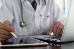 stock image of doctor sitting at a computer and tablet