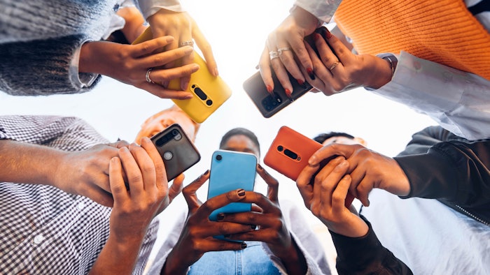 group of people standing in circle and looking phones