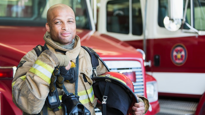 firefighter posing in uniform in front of fire truck