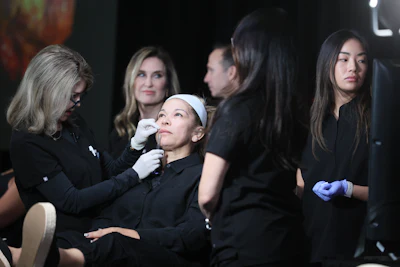 A group of female dermatologists assess a woman's face for cosmetic purposes.