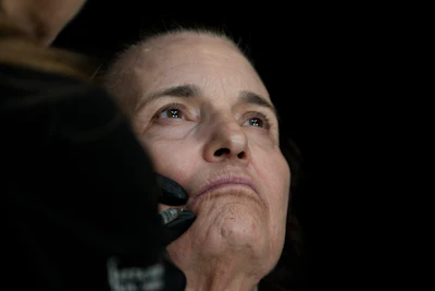 A dermatologist injects botox near an older woman's lips.