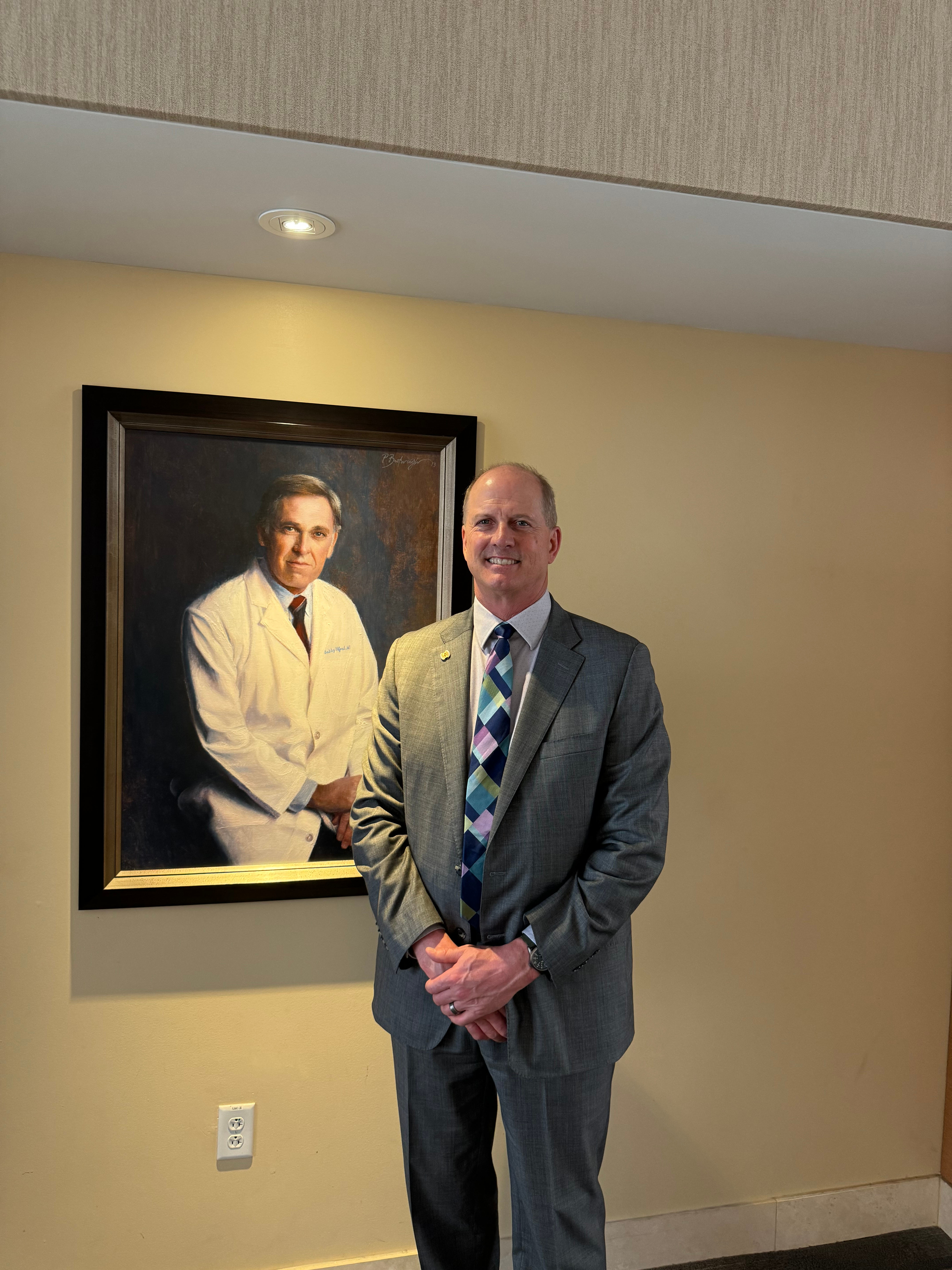 Dr. Backous poses next a portrait of his mentor, the late Bobby R. Alford, MD, former Baylor College of Medicine Chancellor and Distinguished Service Professor.
