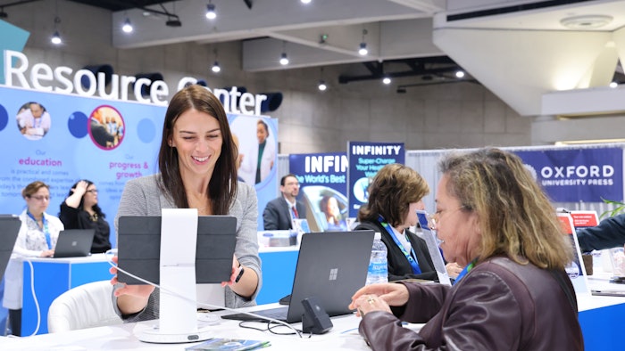 This is a photo of an AAD staff person talking with an attendee at the AAD Resource Center.
