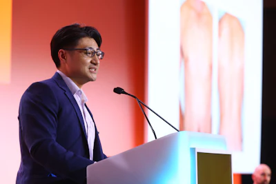 This is a photo of Derm Tank winner Justin Marson, MD speaking at a podium.
