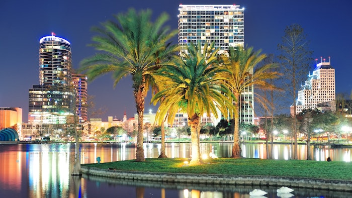 Orlando downtown skyline panorama over Lake Eola at night with urban skyscrapers, tropic palm tree and clear sky.