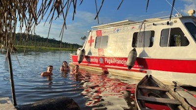The participants enjoy a relaxing bathe in the river. The larger boat is one of the “ambulanchas,” and the smaller is used for fishing.