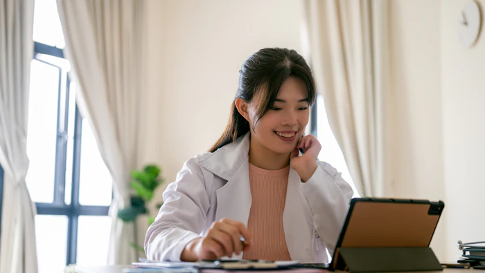 Asian female university student using digital tablet during online education training class at living room