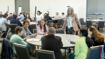 Image of a woman leading a discussion at a round table.