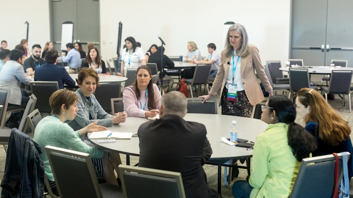 Image of a woman leading a discussion at a round table.