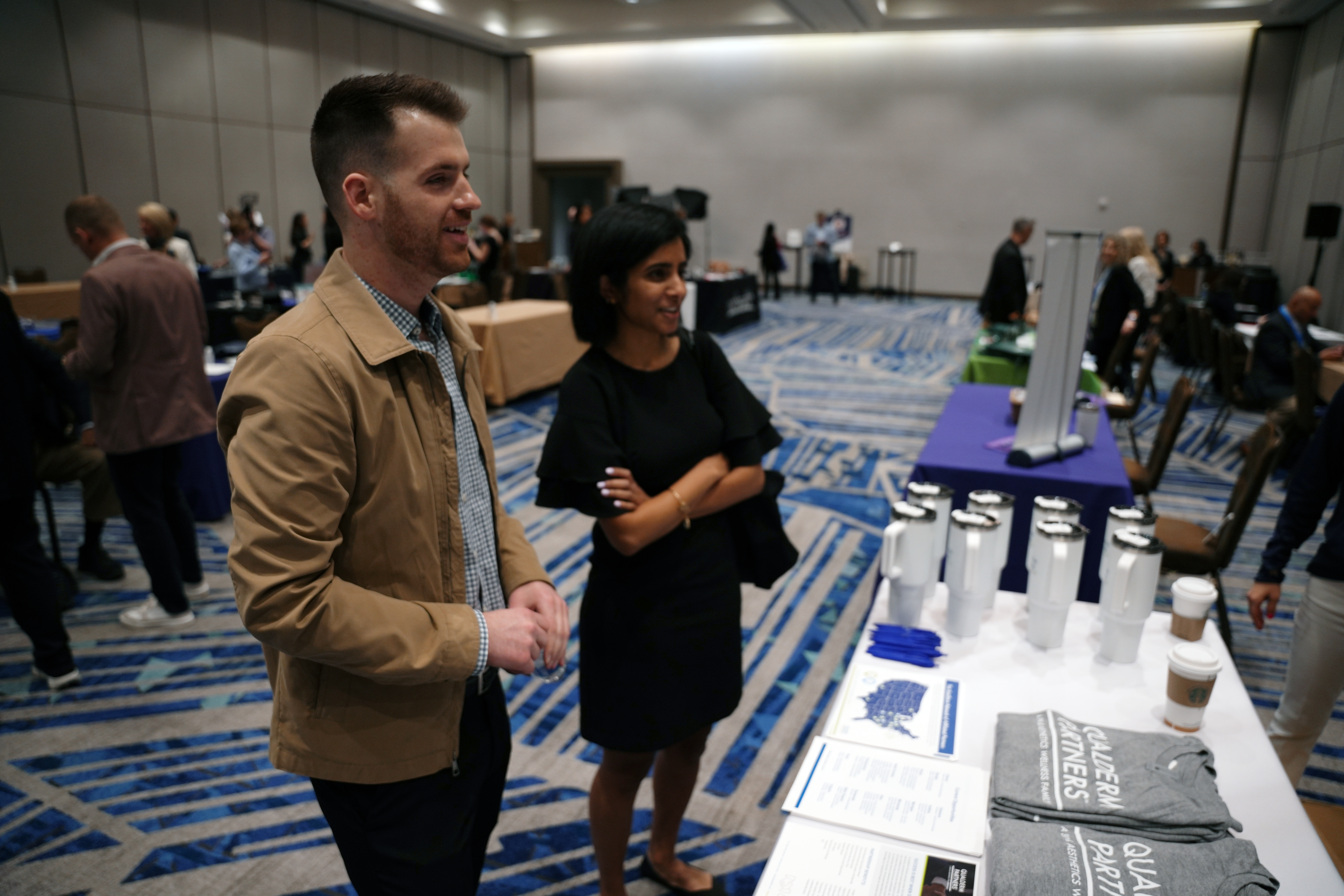 Professional conference scene with attendees near branded display table