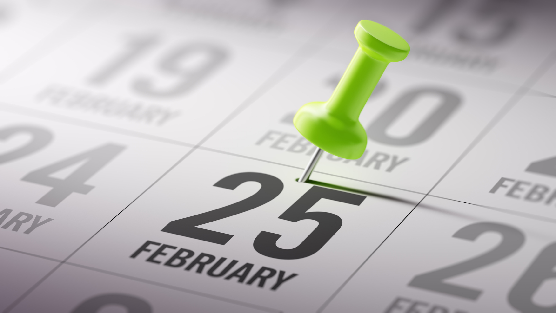 Green pushpin marking February 25th on a calendar