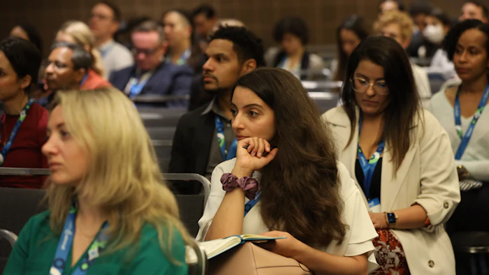 Diverse professionals attending conference, seated in lecture hall with attentive expressions