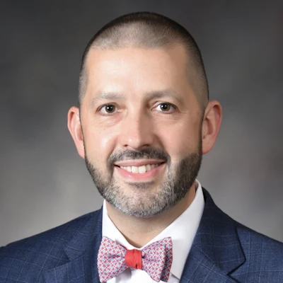 Professional headshot of Dr. Matthew Bush smiling and wearing a suit and bow tie.