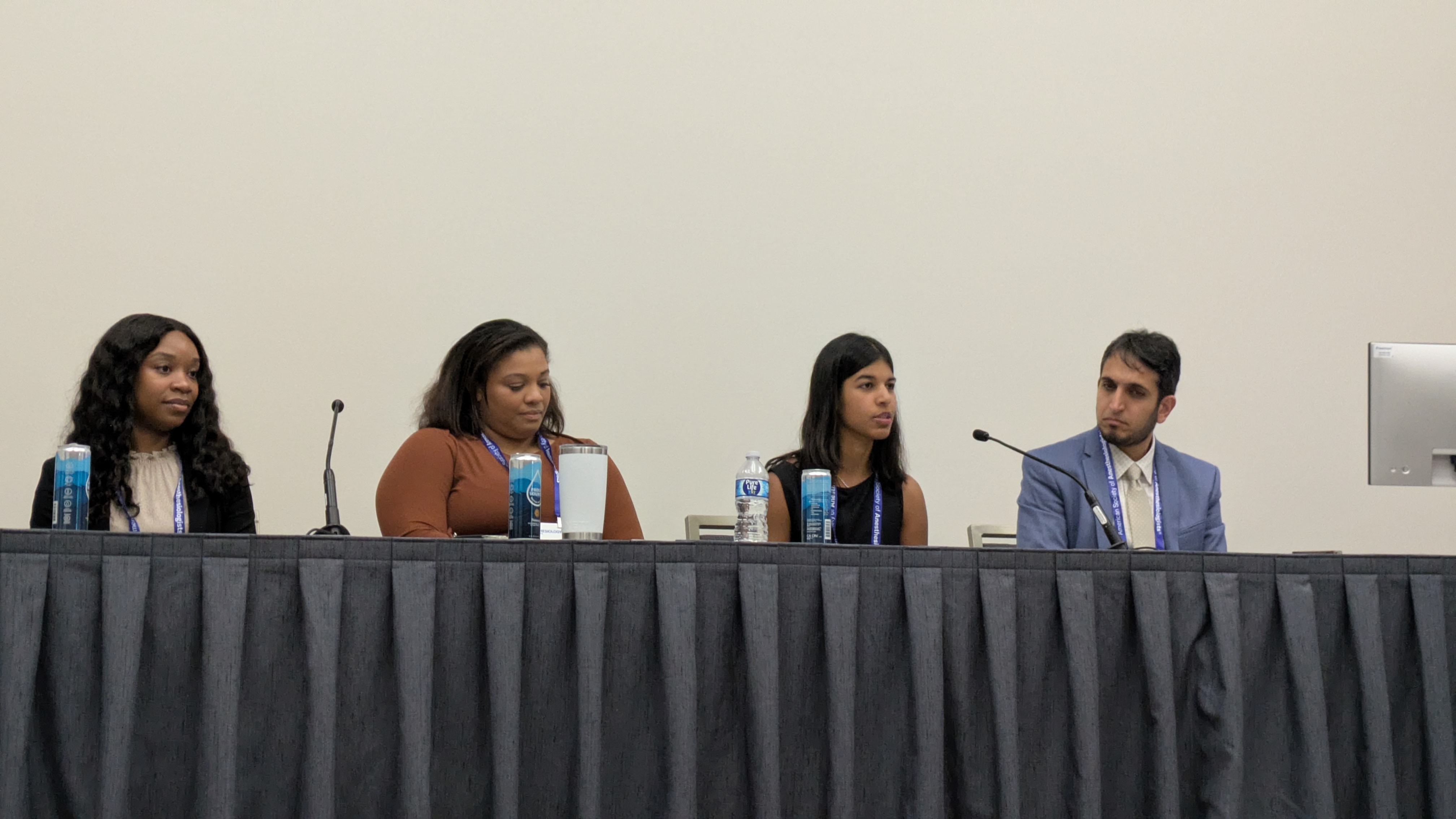 Four panelists seated at a table during a professional conference or panel discussion event