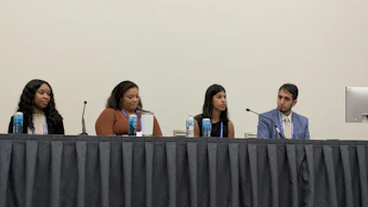 Four panelists seated at a table during a professional conference or panel discussion event