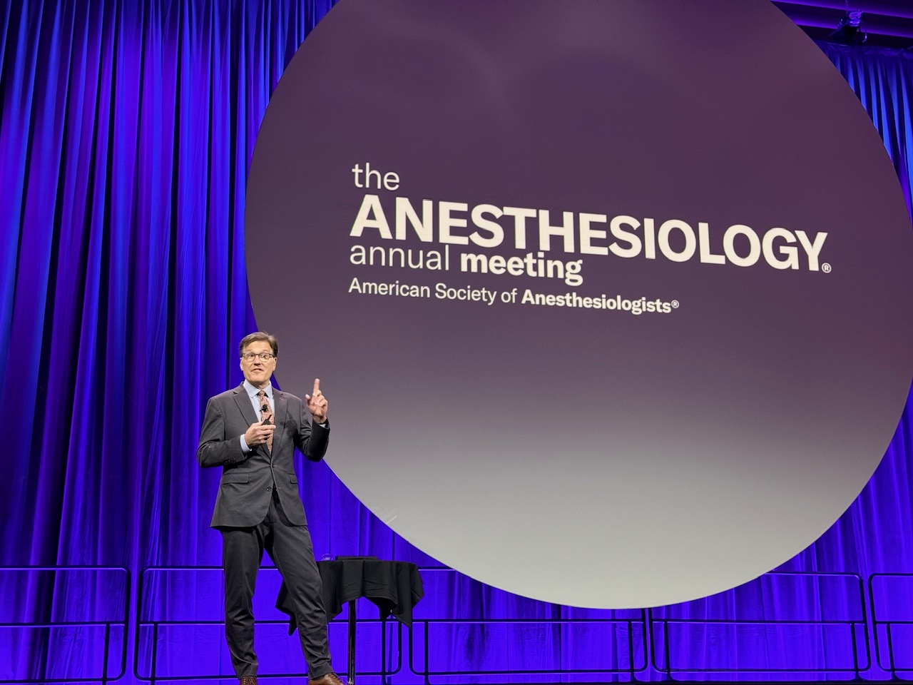 Speaker presenting at the Anesthesiology annual meeting with ASA logo displayed on large screen behind him