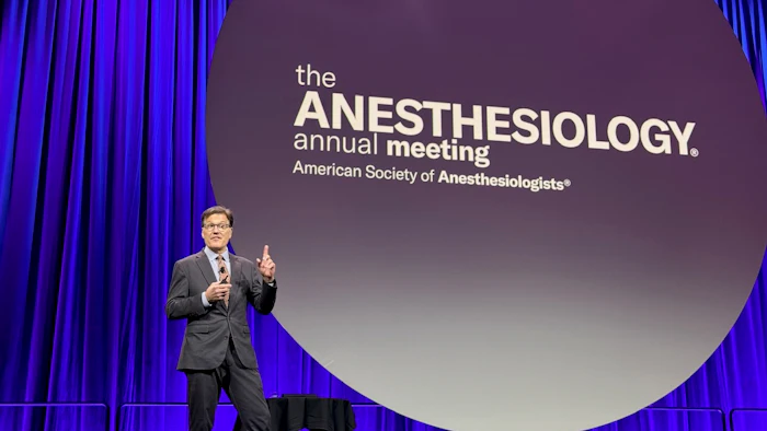 Speaker presenting at the Anesthesiology annual meeting with ASA logo displayed on large screen behind him