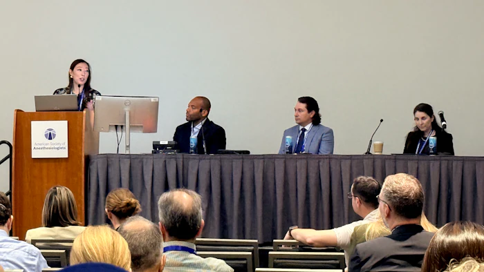 Professional panel discussion with four speakers seated at a table and audience members in foreground at a conference event.