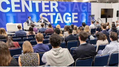 Audience seated at a conference panel discussion with 'Centerstage' signage visible on blue backdrop behind speakers
